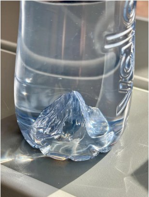 A clear plastic water bottle with the shape of the Matterhorn moulded into its base
