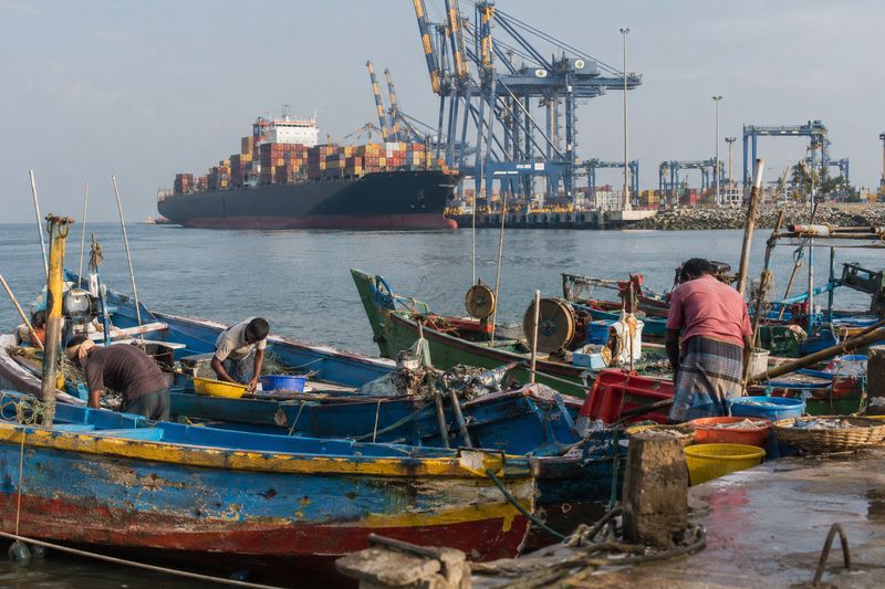 Fishing boats in a south Indian port with a large container ship beyond